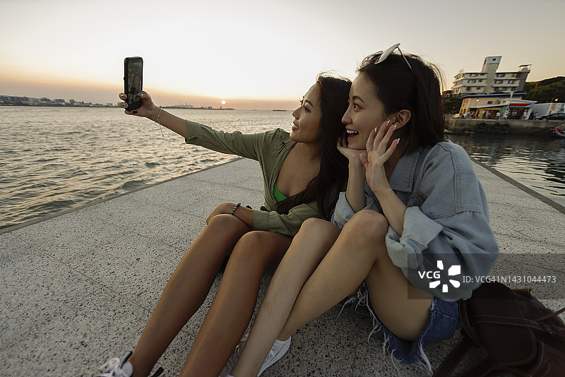两名女子在旅游景点以日落为背景自拍图片素材