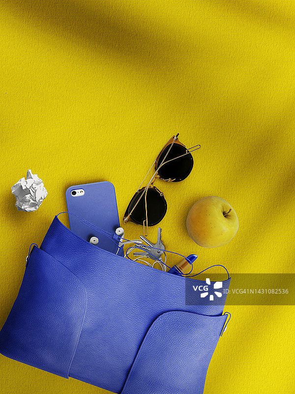 黄色背景中女士手提包内的物品，俯视图图片素材