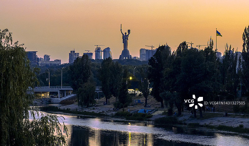 在充满活力的桃色天空下的祖国母亲和乌克兰国旗图片素材