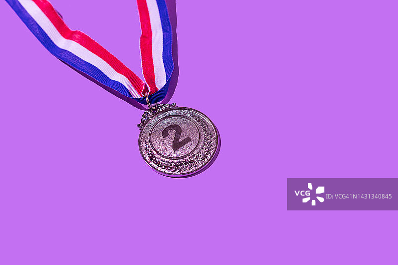 紫色背景上的银牌，数字为2，代表第二名，获胜者、奖牌、荣誉、妇女节、获胜女性、职场女性和体育竞赛概念图片素材