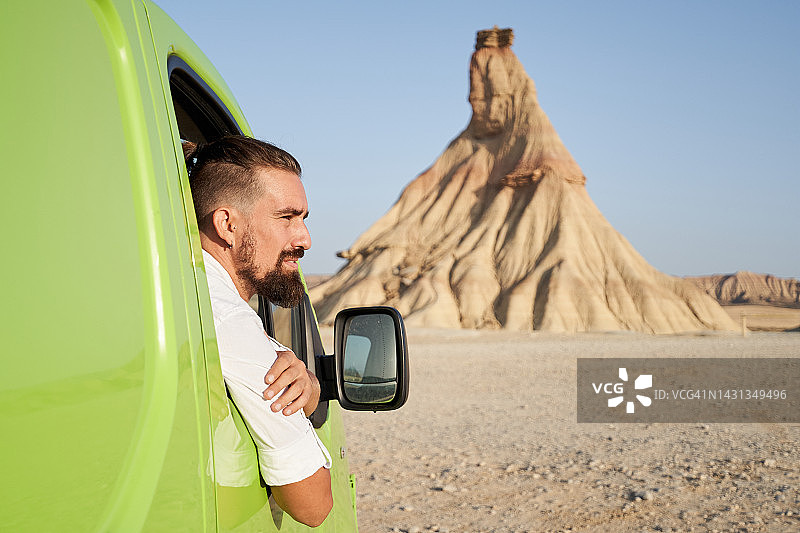 年长的白人男性从车窗探出头观看沙漠风光的留白照片图片素材