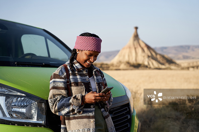 年轻女士查看在线地图搜索路线，站在绿色汽车外靠在车上的快乐照片图片素材