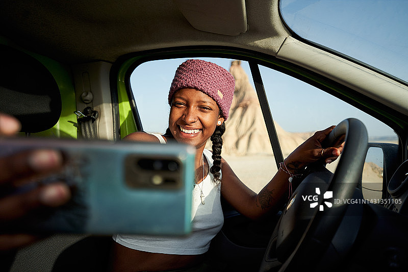 快乐的非裔美国女性在车内自拍，背景是沙堡图片素材