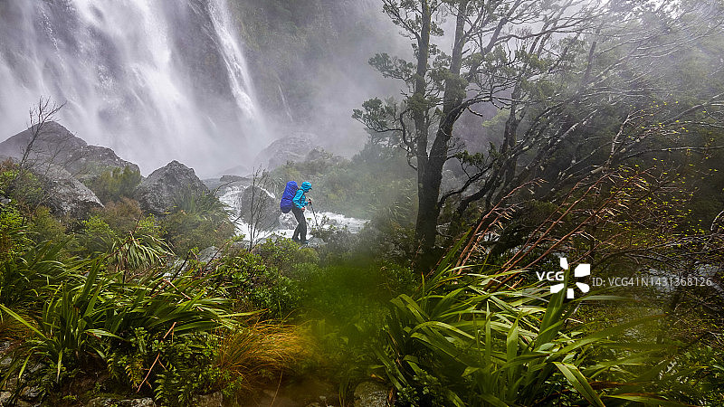 女背包客在咆哮的厄兰瀑布前徒步，新西兰峡湾国家公园图片素材