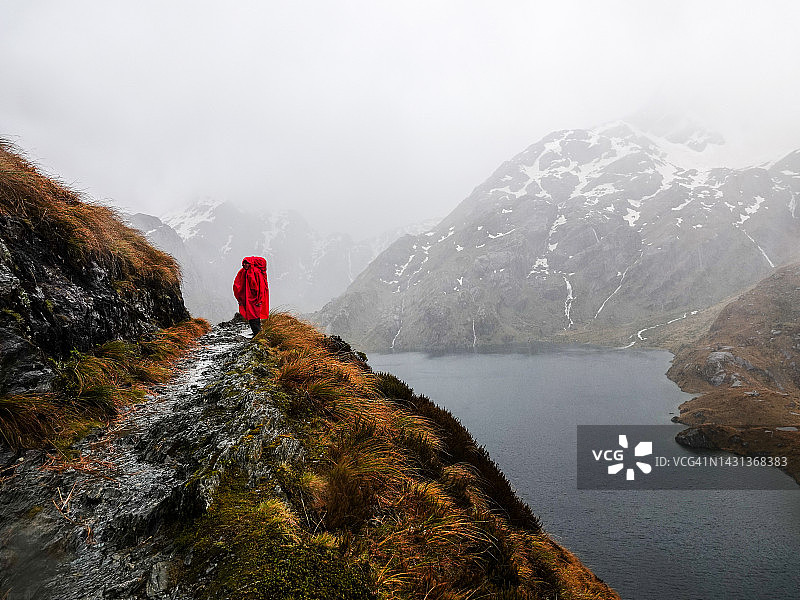 身穿雨具的背包女游客，新西兰哈里斯峰图片素材