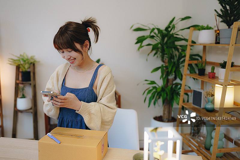 亚洲女性扫描运输箱上的二维码图片素材