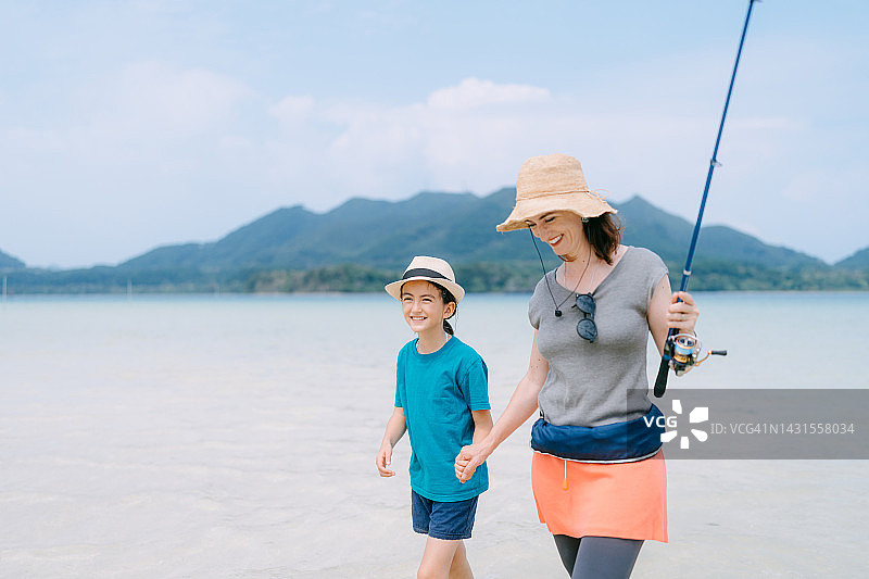 热带浅水区手持钓鱼竿的母女图片素材