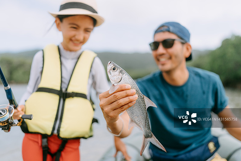 父女展示从皮划艇钓到的鱼图片素材