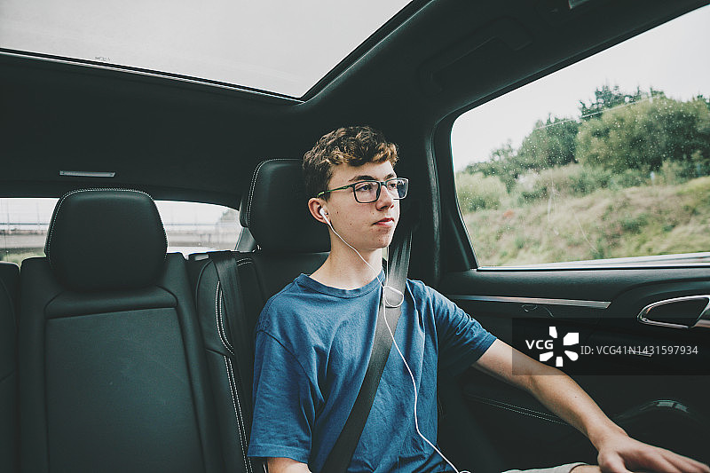 青少年坐在汽车后座听音乐图片素材