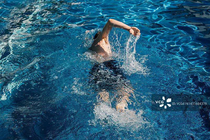 男人在游泳池里游泳，高角度视图图片素材