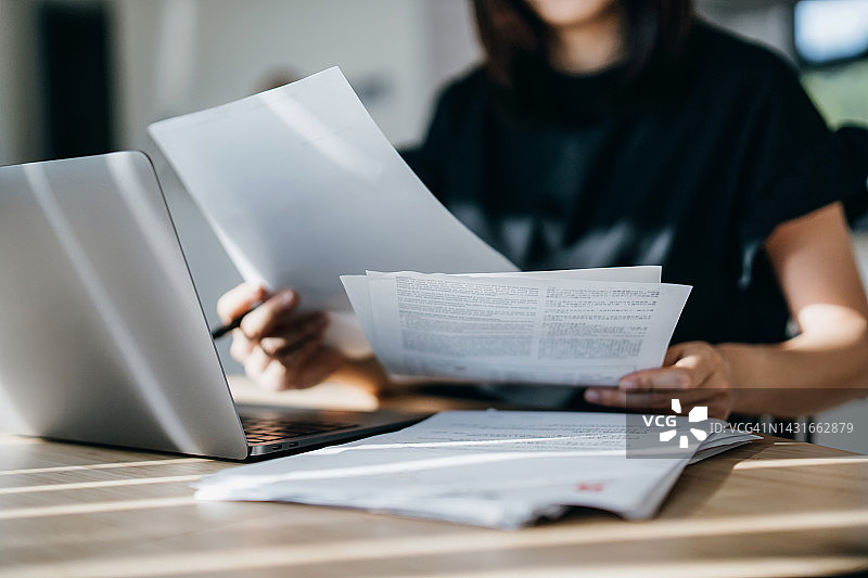 亚洲女人在家用笔记本电脑处理个人银行业务和财务，计划预算和计算开支图片素材