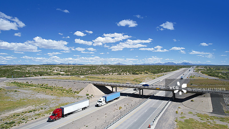 美国德克萨斯州10号州际公路上行驶的红蓝半挂卡车 - 无人机视角图片素材