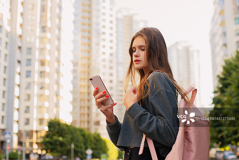 微笑的休闲女人背着背包使用手机图片素材