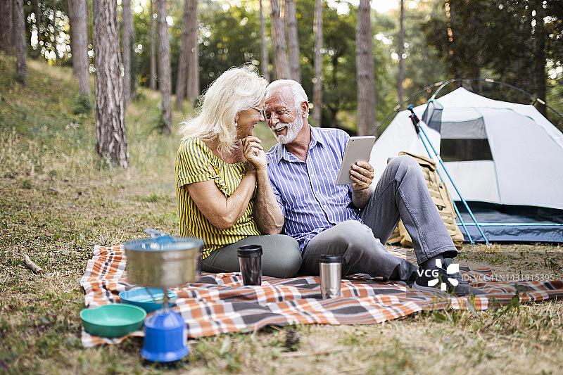 年长的夫妇在秋季露营旅行中使用平板电脑图片素材