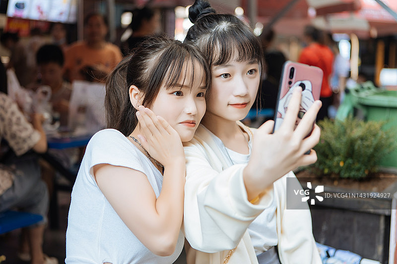 两个年轻女孩在城市自拍，展现都市生活图片素材