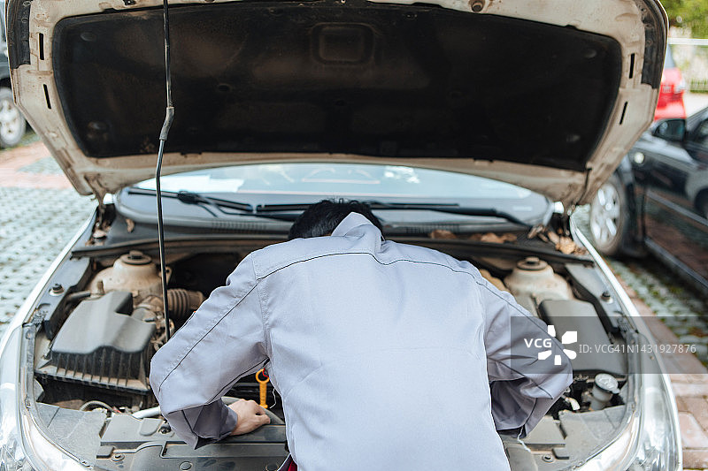 男人在检查他的汽车——都市生活方式图片素材