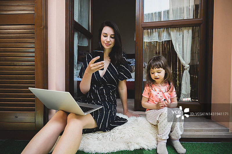 在家带孩子工作的女人。女性商业、母亲、自由职业、家庭办公室的概念图片素材