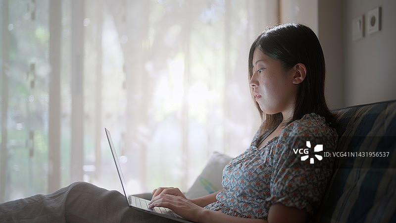 年轻女人在旅途中的酒店房间里使用笔记本电脑图片素材