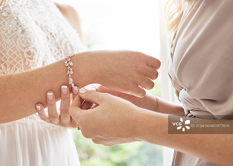 婚礼上新娘和伴娘帮忙佩戴珠宝手镯，打造优雅经典时尚魅力。昂贵的新娘钻石配饰，为特殊仪式日打造优雅风格特写。图片素材