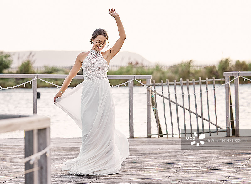 婚礼，新娘身着礼服在户外湖边，美丽、时尚而幸福。爱、自由和美丽的女人用奢华的面料跳舞，并对乡村婚姻庆典感到高兴图片素材