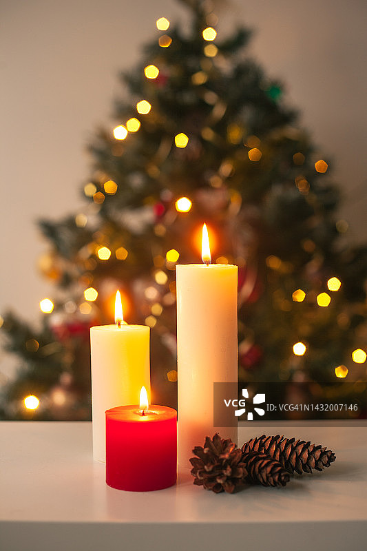 家居装饰中的白色和红色蜡烛，模糊的灯光和圣诞树背景图片素材