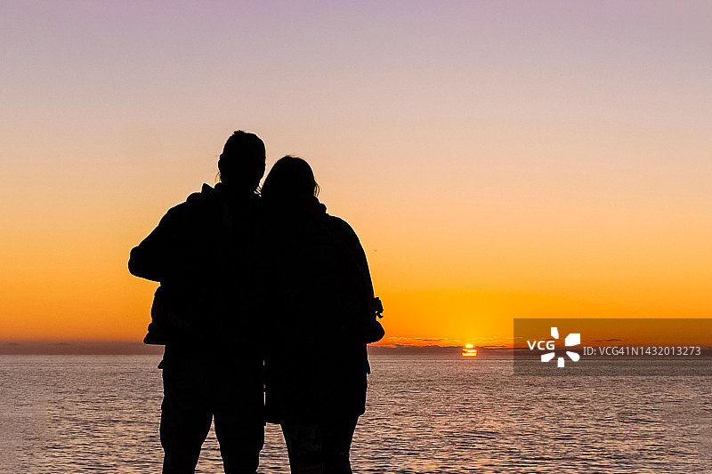 海边日落时拥抱的情侣轮廓图片素材