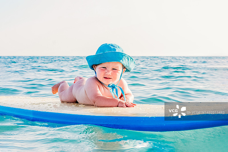 可爱的宝宝躺在海中的冲浪板上图片素材