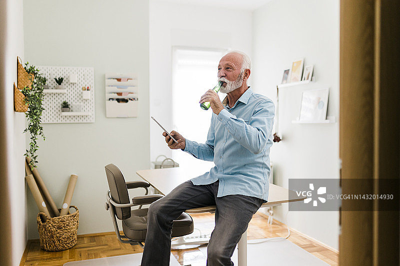 老年男人在视频通话时喝啤酒图片素材
