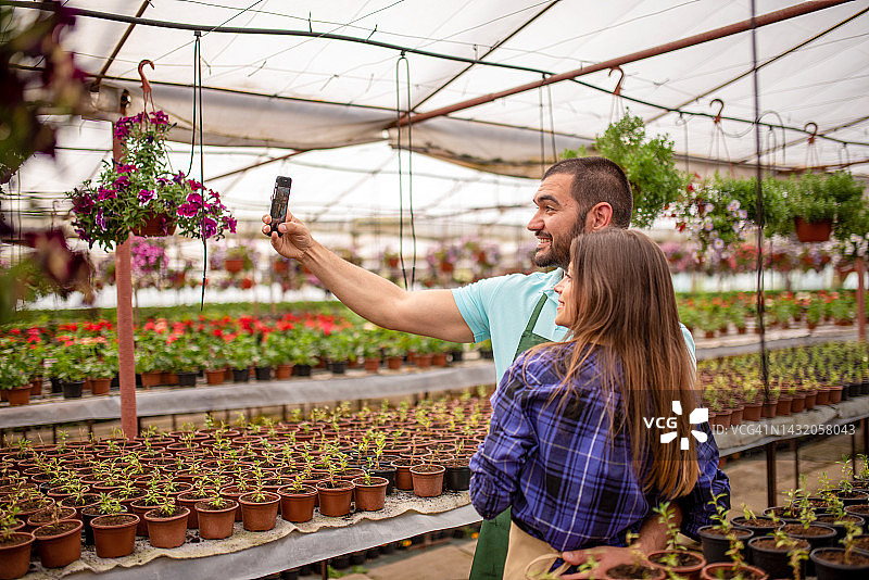 快乐的年轻园丁在工作场所用手机自拍图片素材