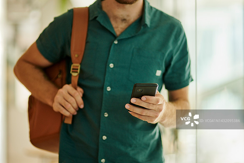 男人携带背包和手机，在迪拜的家、办公室或住所行走，用于社交媒体、电子邮件或网络通讯图片素材