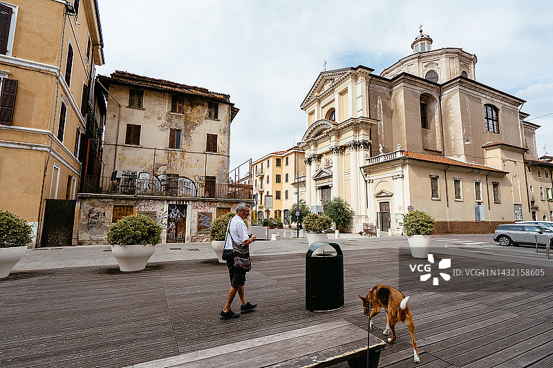 男子带狗走在旧城区的圣洛伦佐教堂旁图片素材