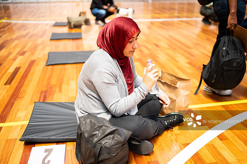 戴着头巾的难民妇女在避难所喝水图片素材