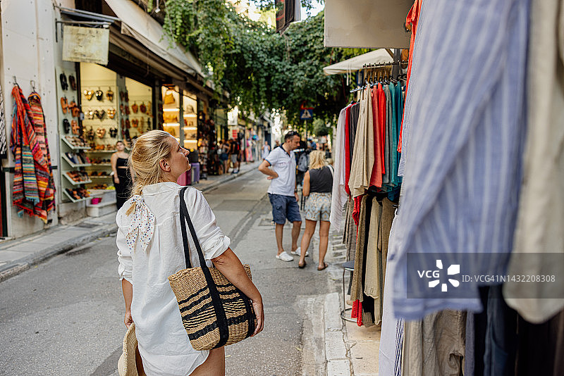 夏季，中年妇女带着包在城市集市上游览图片素材