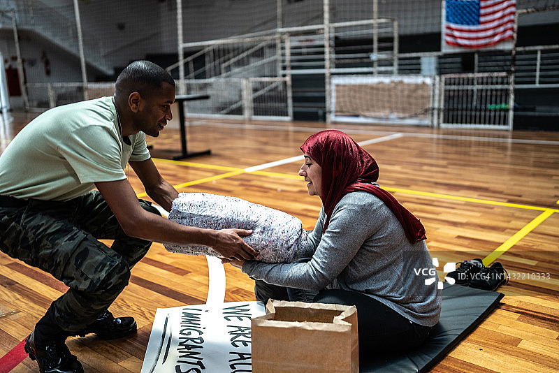 戴着头巾的中年妇女在避难所接受捐赠图片素材