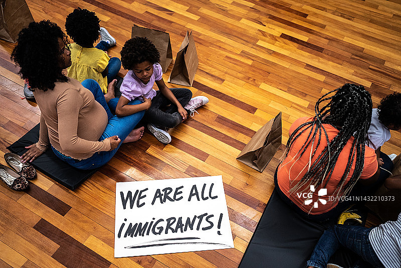 庇护所内难民家庭与“我们都是移民”标语图片素材