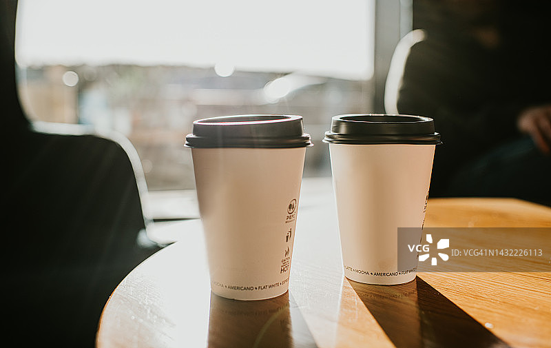 木桌上的外卖咖啡杯和阴影图片素材
