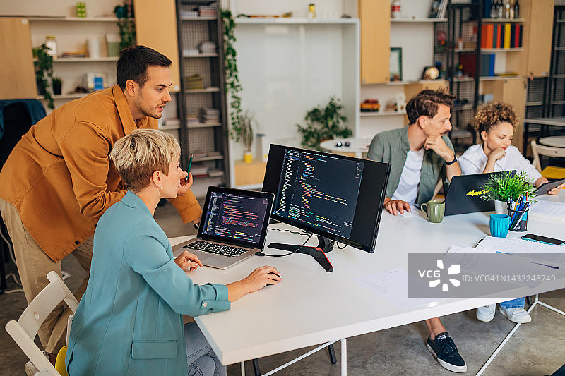 女人学习编程，男同事帮助她，屏幕上显示代码图片素材