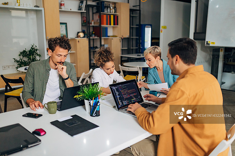 办公室里，不同背景的人们在同一张会议桌旁学习编程图片素材