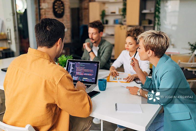 一小群人围坐在会议桌旁学习编程图片素材