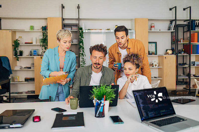 一小群人在办公室学习编程，都看着笔记本电脑屏幕图片素材
