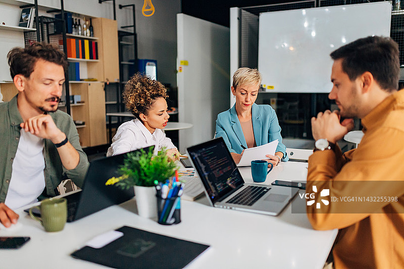 一群人正在讨论编程技术，他们使用笔记本电脑图片素材
