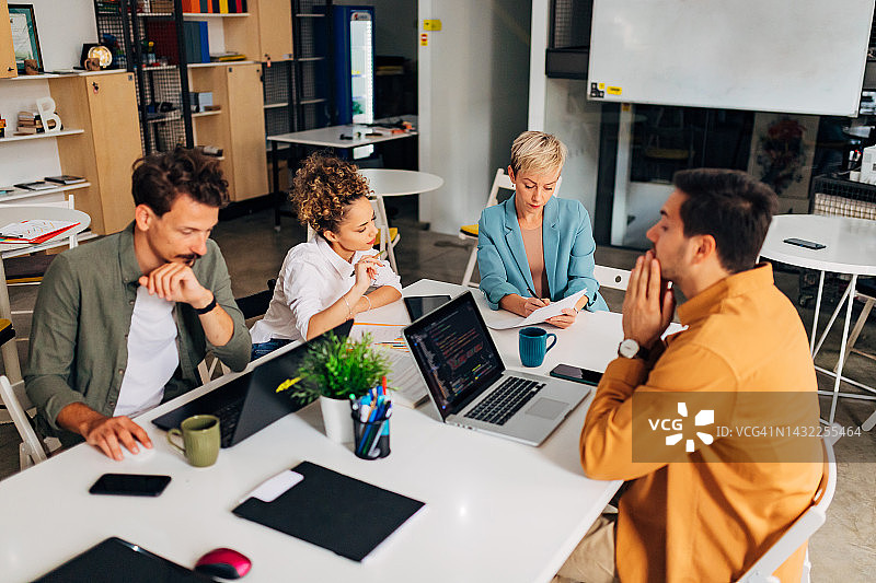 男士使用笔记本电脑，IT专家讲解编码技术。西班牙裔女性认真听取教育者的讲解并做笔记图片素材