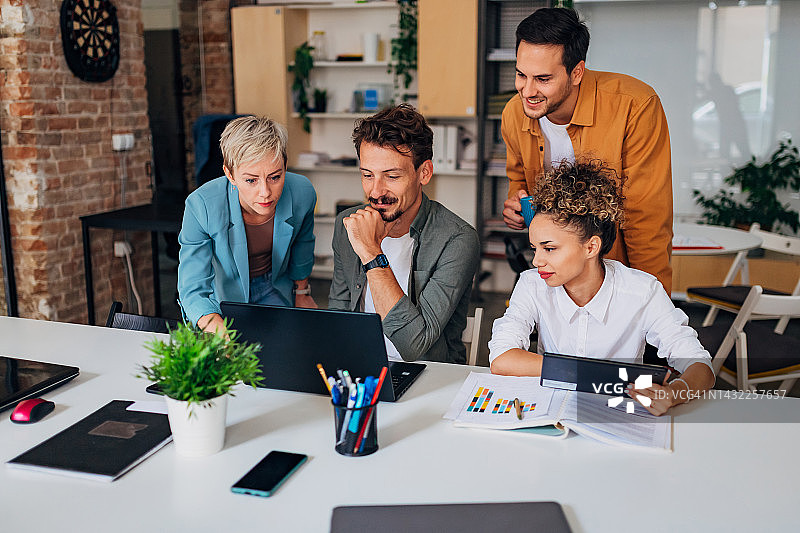 办公室里，同事团队在一台笔记本电脑上工作，掌握编程语言和编码技术图片素材