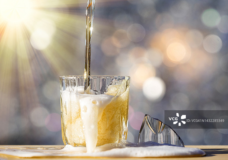 阳光照射下，啤酒杯摔碎在地面上图片素材