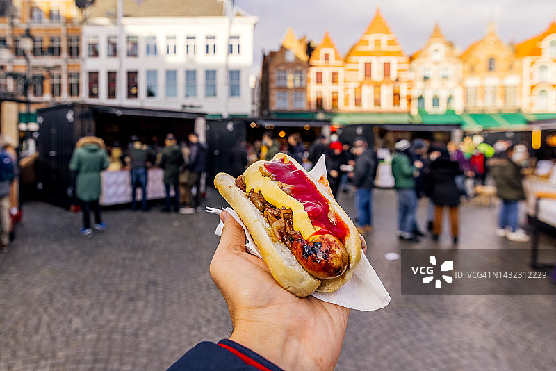 在比利时布鲁日圣诞市场吃香肠面包的男人图片素材