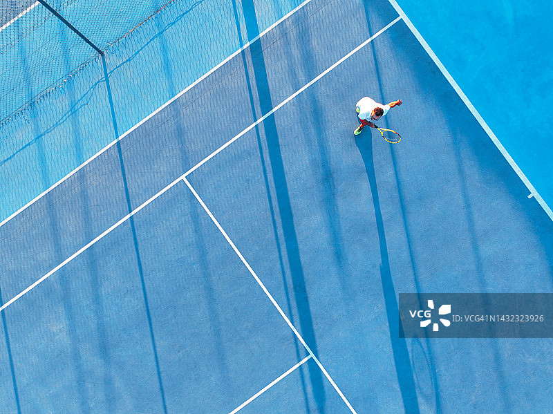 年轻男人在蓝色硬地球场上打网球的航拍景观图片素材