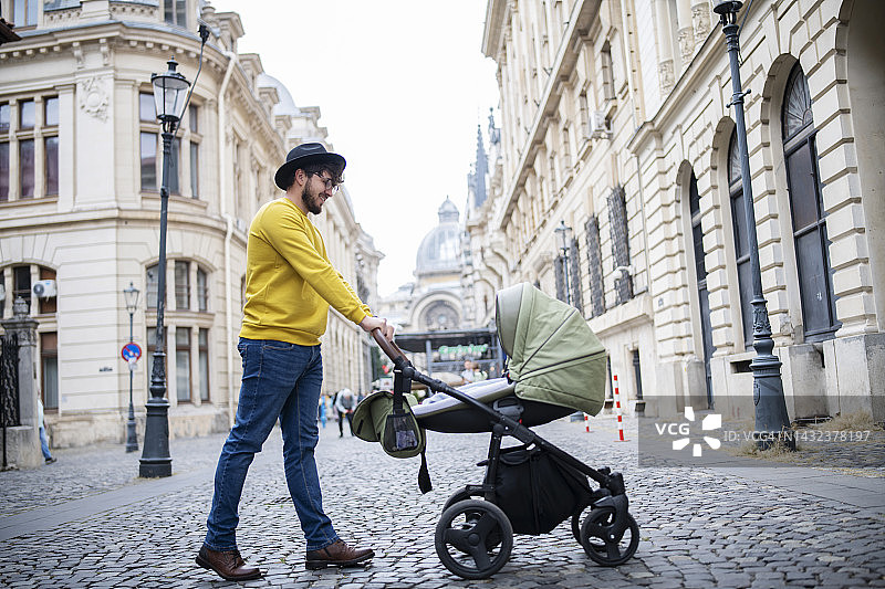 年轻的父亲在城市里散步图片素材
