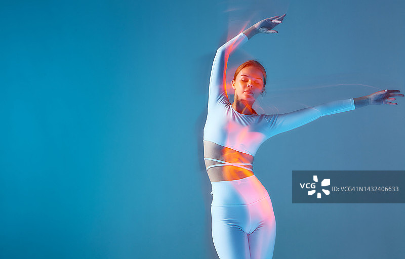 做弯腰运动的漂亮运动女孩，白色运动服健身模特在蓝色背景上的独立人像图片素材