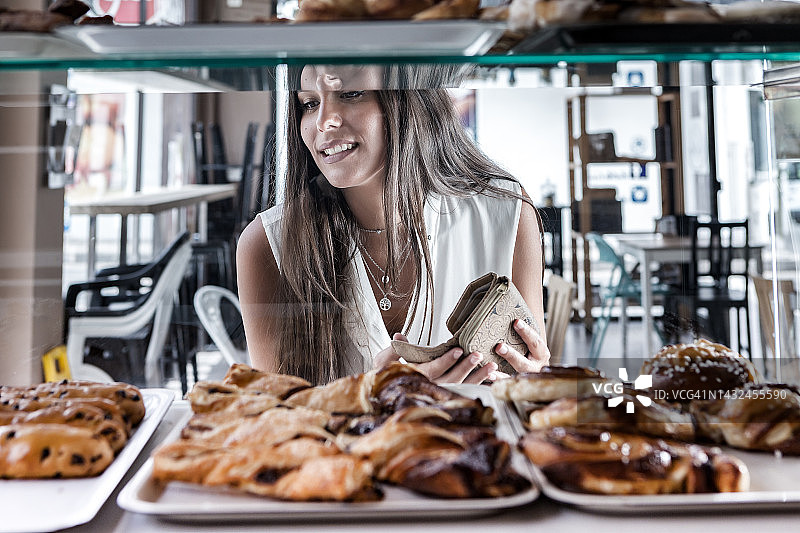 快乐的棕发女子在自助餐厅购买小圆面包图片素材