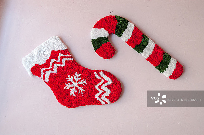 圣诞节装饰品，纺织垫上的圣诞老人袜子和糖果手杖，水平视角的粉红色背景图片素材